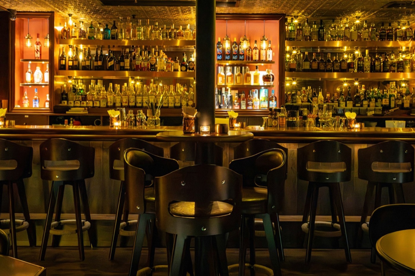 Dimly lit shelved wine bottles behind the bar